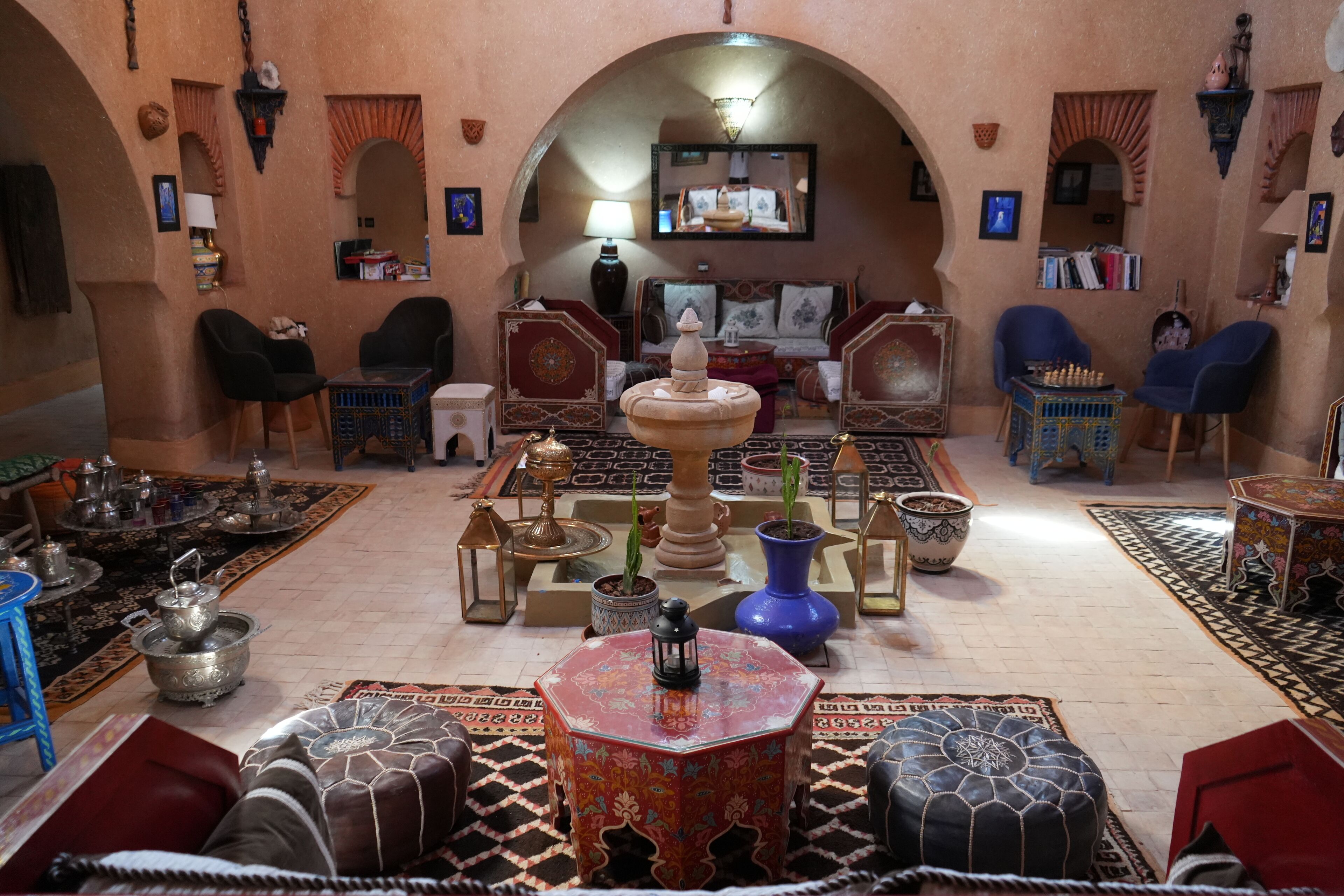 Un interior tradicional con una fuente central, zonas de estar y objetos decorativos.