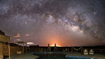 Een buitenzwembad, ligstoelen bij het zwembad