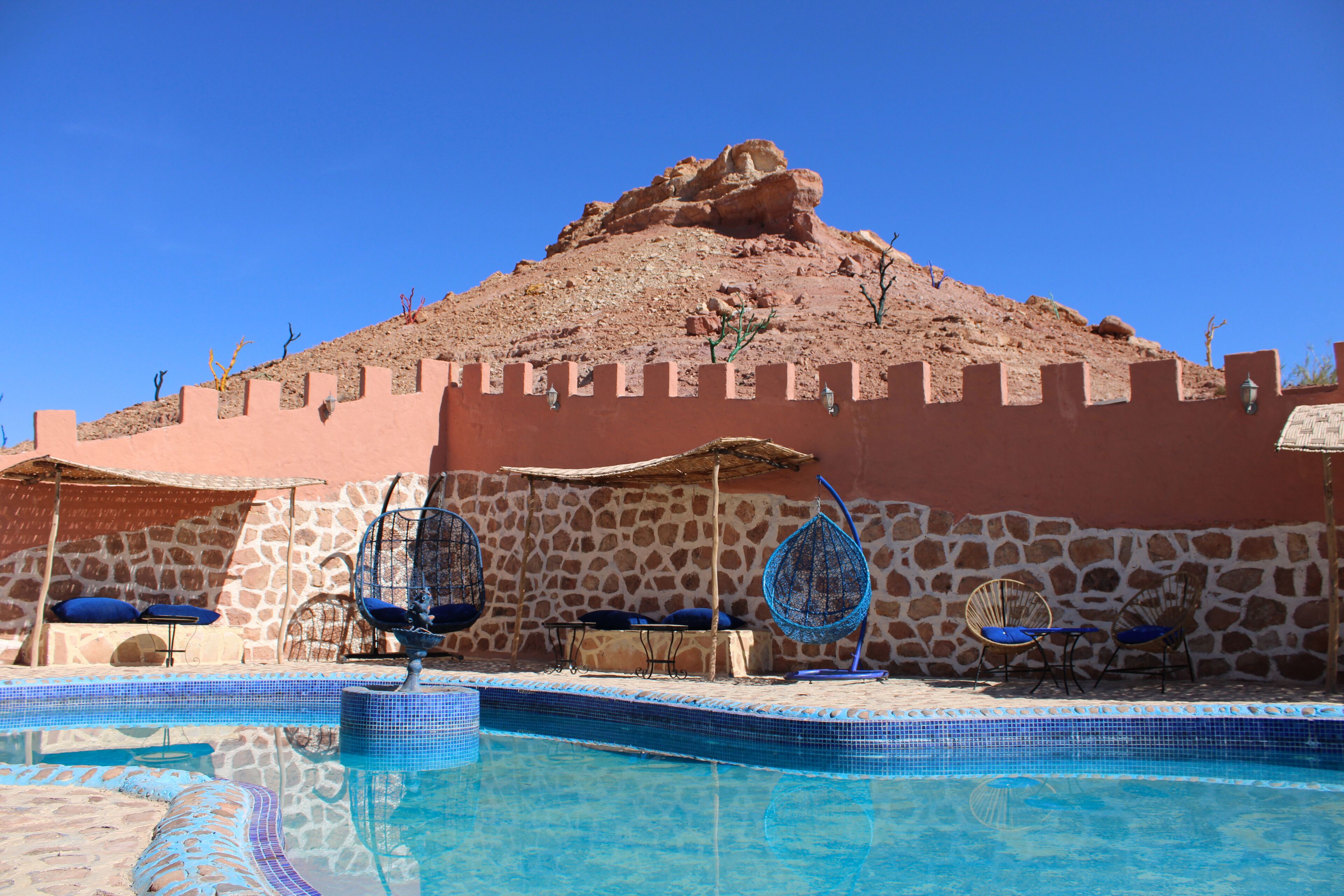A swimming pool with a stone wall and a rock formation in the background.
