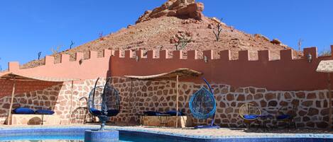 Una piscina con un muro de piedra y una formación rocosa al fondo.