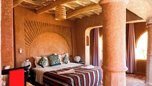 Una habitación amplia con una cama grande, un televisor rojo y una alfombra de cuero de vaca.