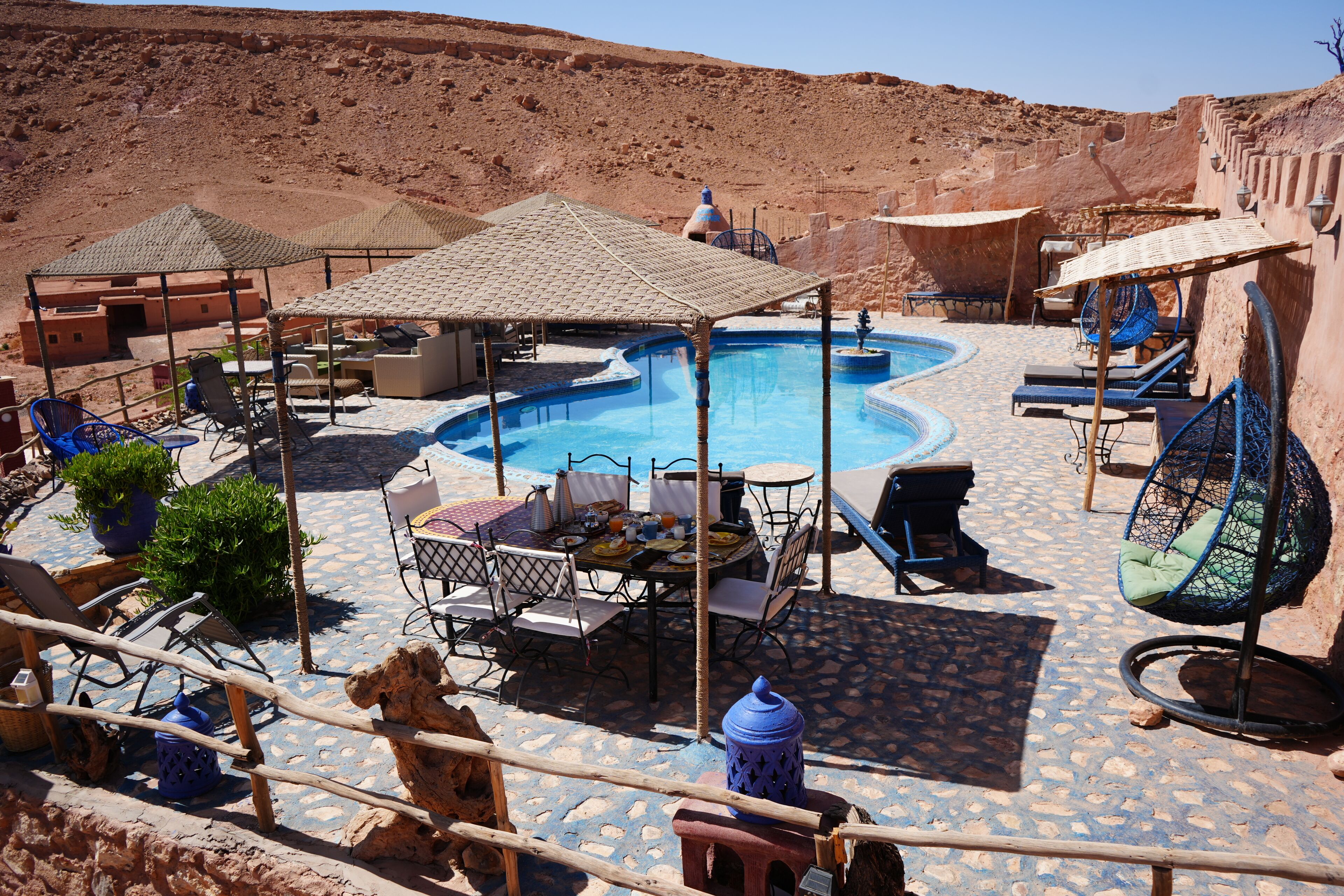 A pool area with lounge chairs, a table, and umbrellas.