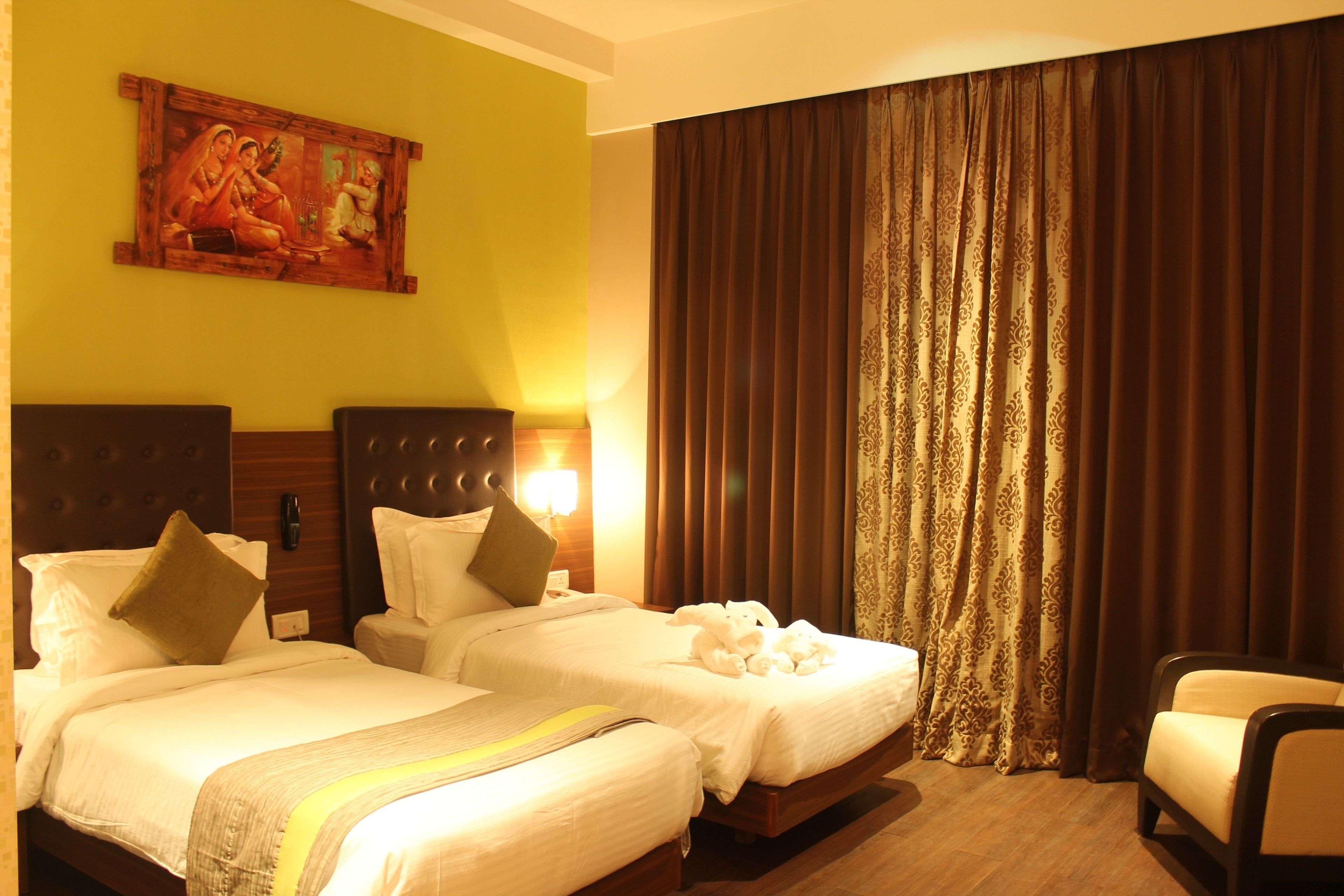 A hotel room with two beds, a painting on the wall, a large window with curtains, and a chair.