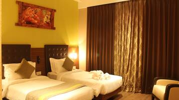 A hotel room with two beds, a painting on the wall, a large window with curtains, and a chair.