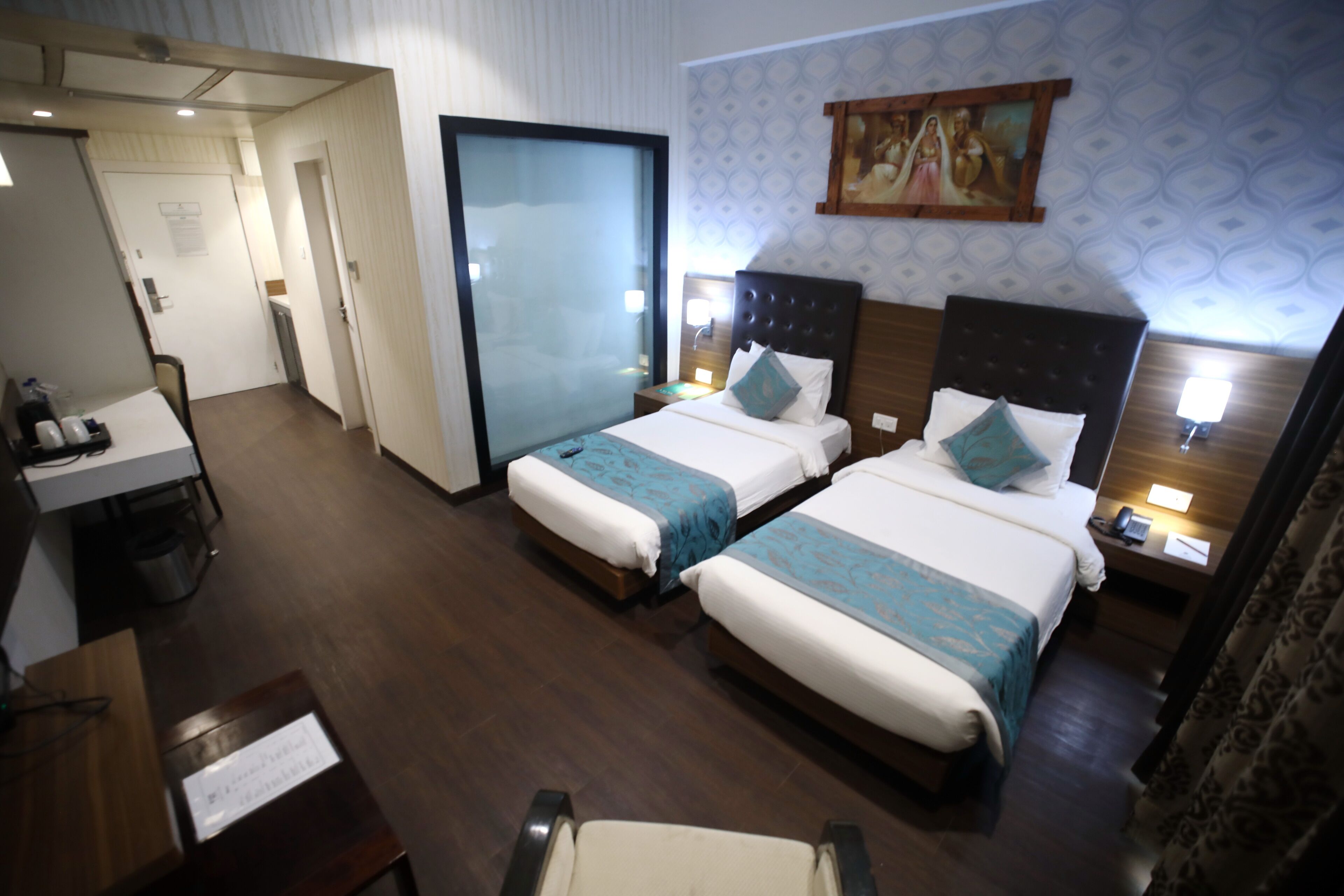 Habitación de hotel con dos camas, un escritorio y una silla.