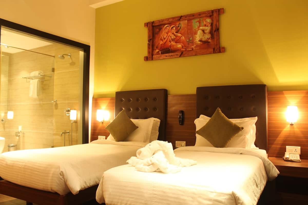 Quarto de hotel com duas camas, chuveiro e um quadro na parede.