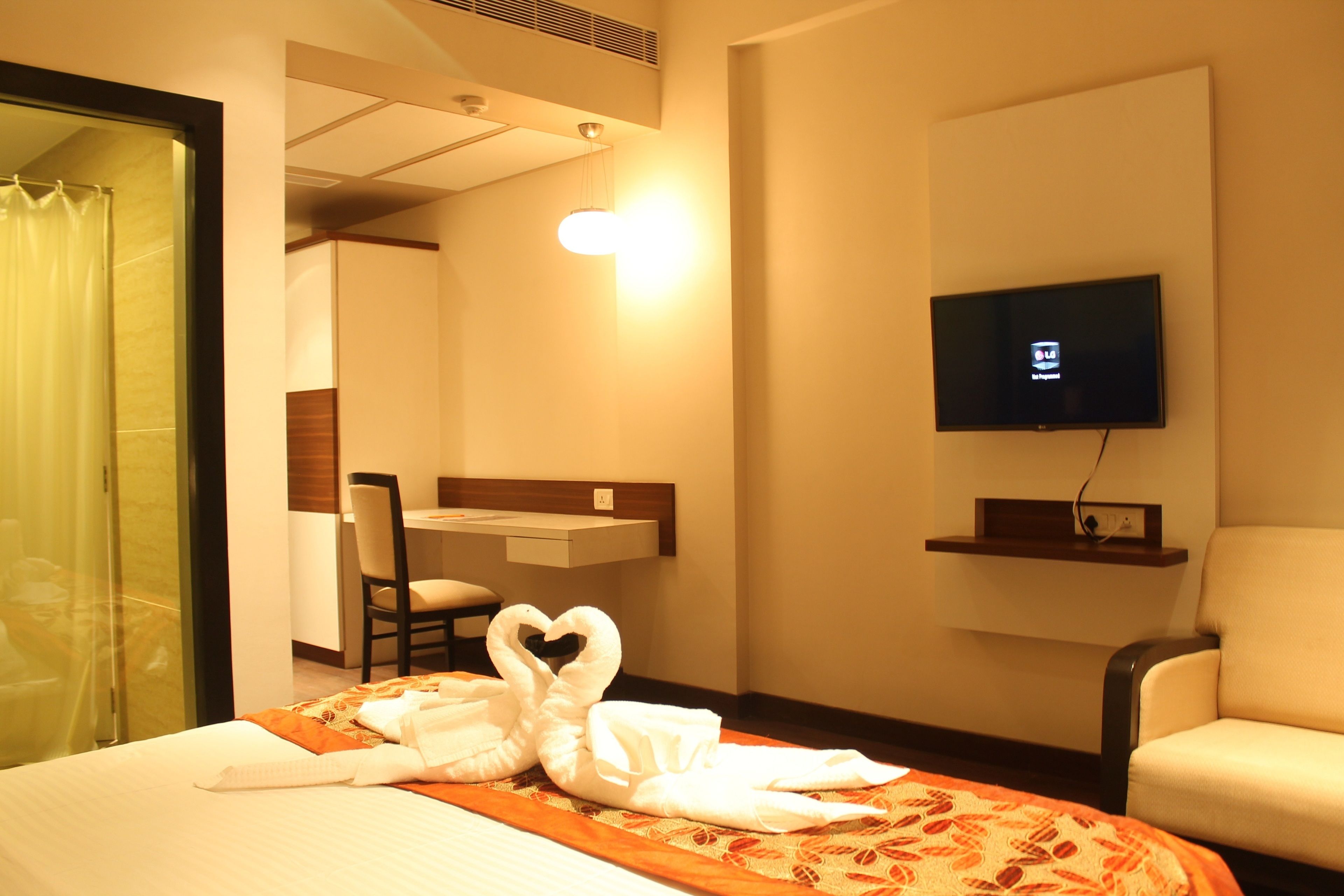 A hotel room with a bed, a desk, a TV, and a chair.