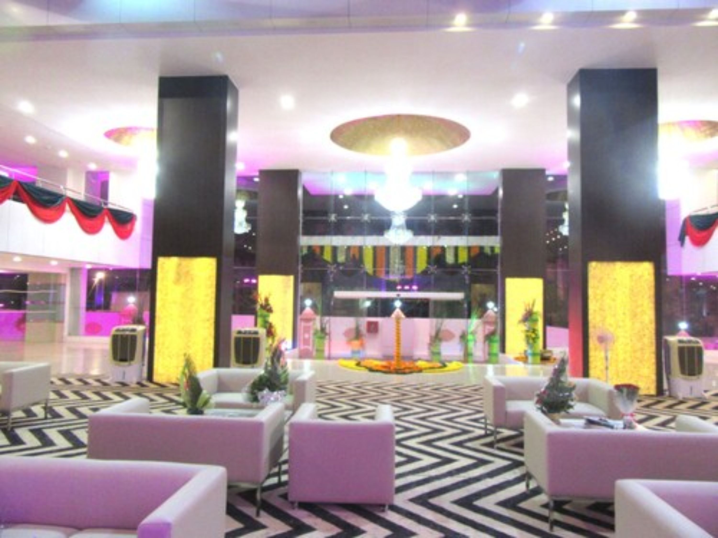Eine Lobby mit einer zentralen Rezeption, einer Sitzecke mit Sofas und einem gemusterten Boden.