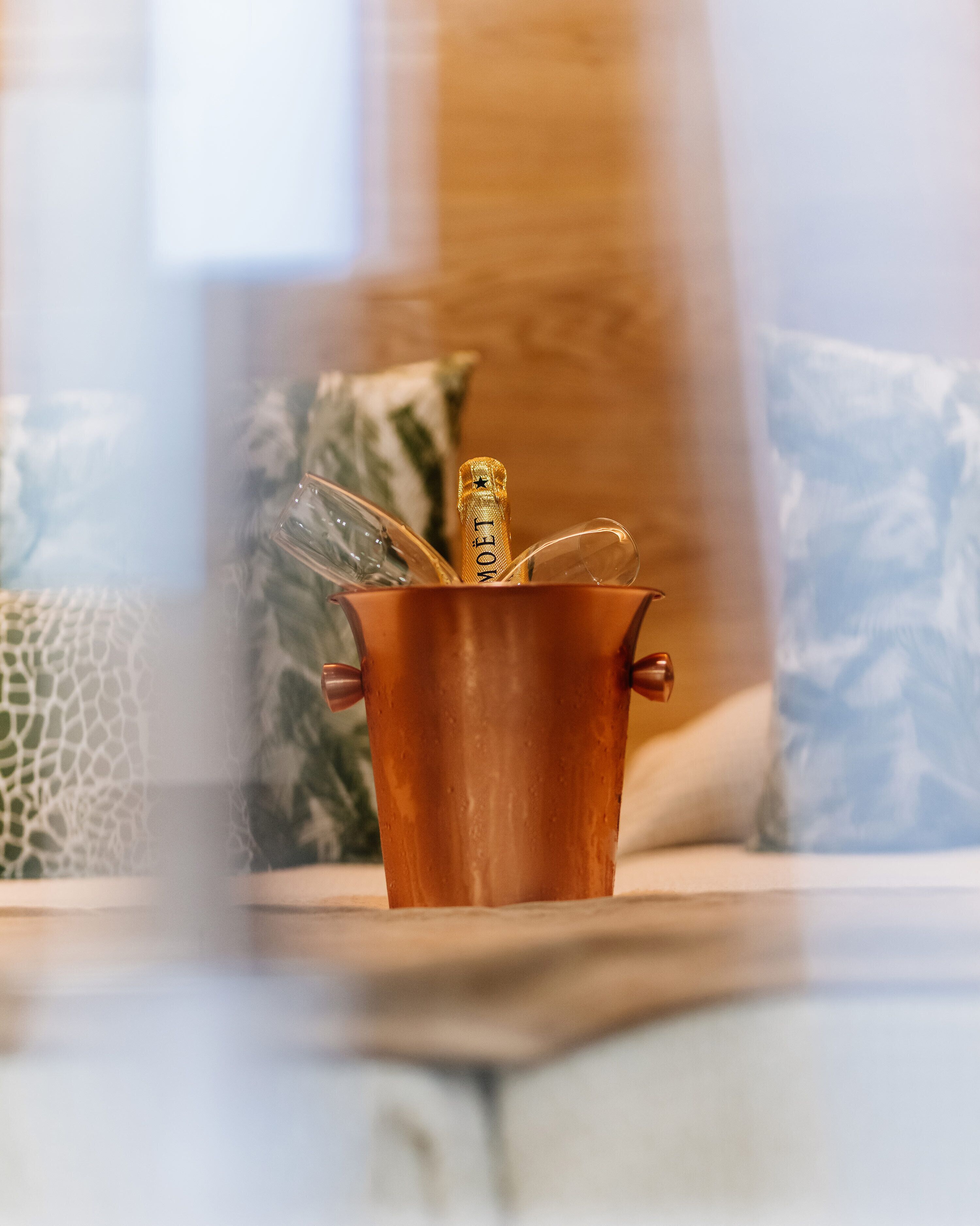 Un recipiente de cobre con una botella etiquetada "MOET" sobre una mesa.