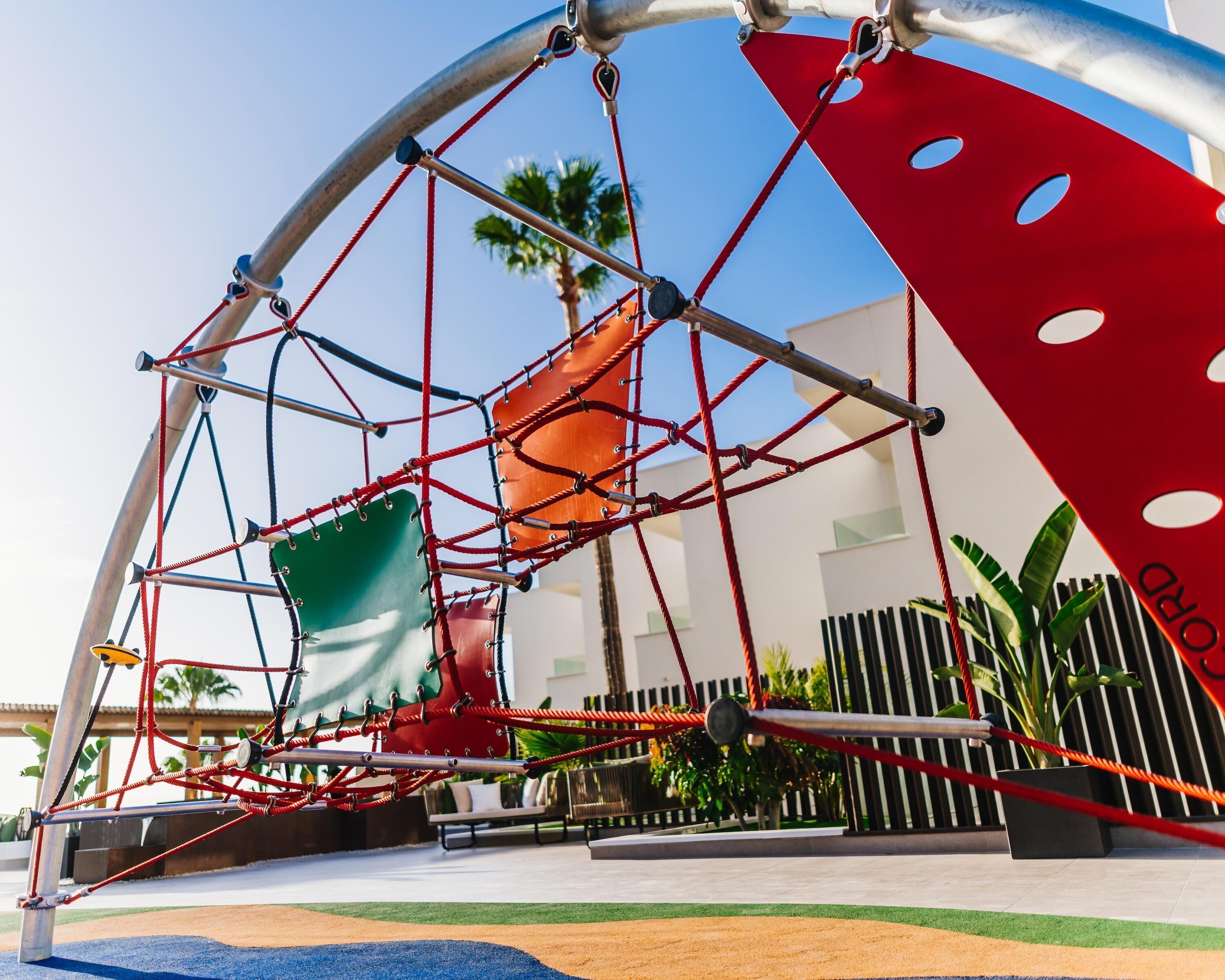 A playground with a climbing structure and swings.