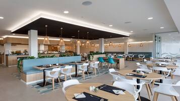 A modern restaurant with a central bar area, multiple seating options including round tables and booths, and pendant lighting.