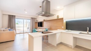 Une cuisine moderne dotée d’un îlot central, un coin repas avec une table et des chaises, et un espace de vie avec un canapé.