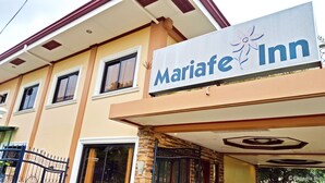 Un hotel llamado Maria Inn con un letrero, pilares de piedra y una entrada con reja.