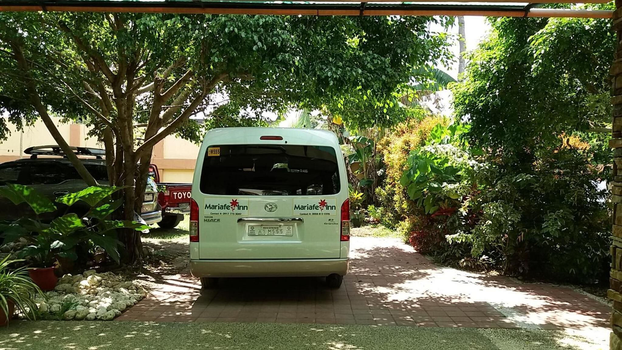 A white van parked in a driveway with a Mariafe Inn logo on the back.