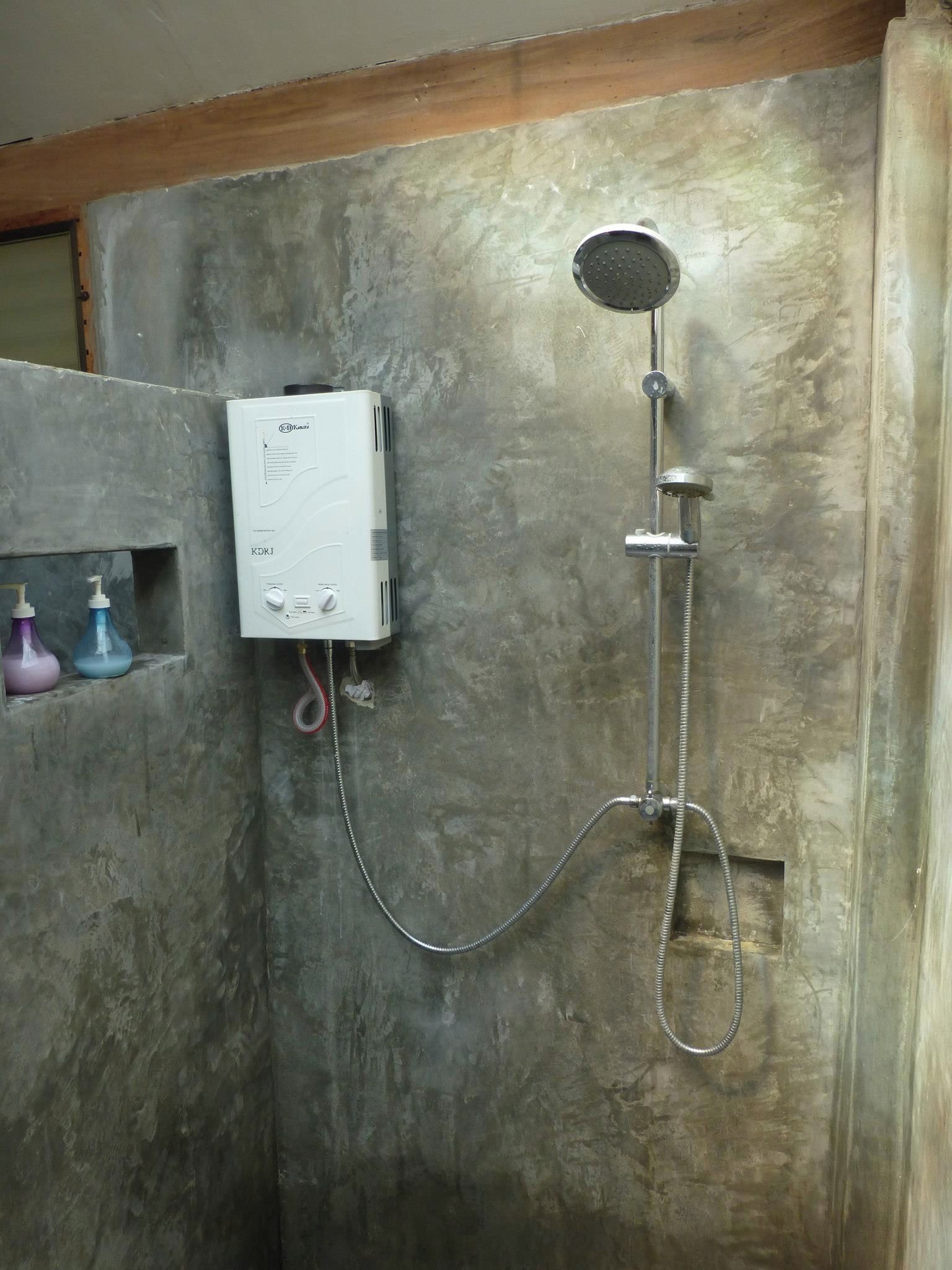 A shower with a handheld showerhead and a wall-mounted control unit.