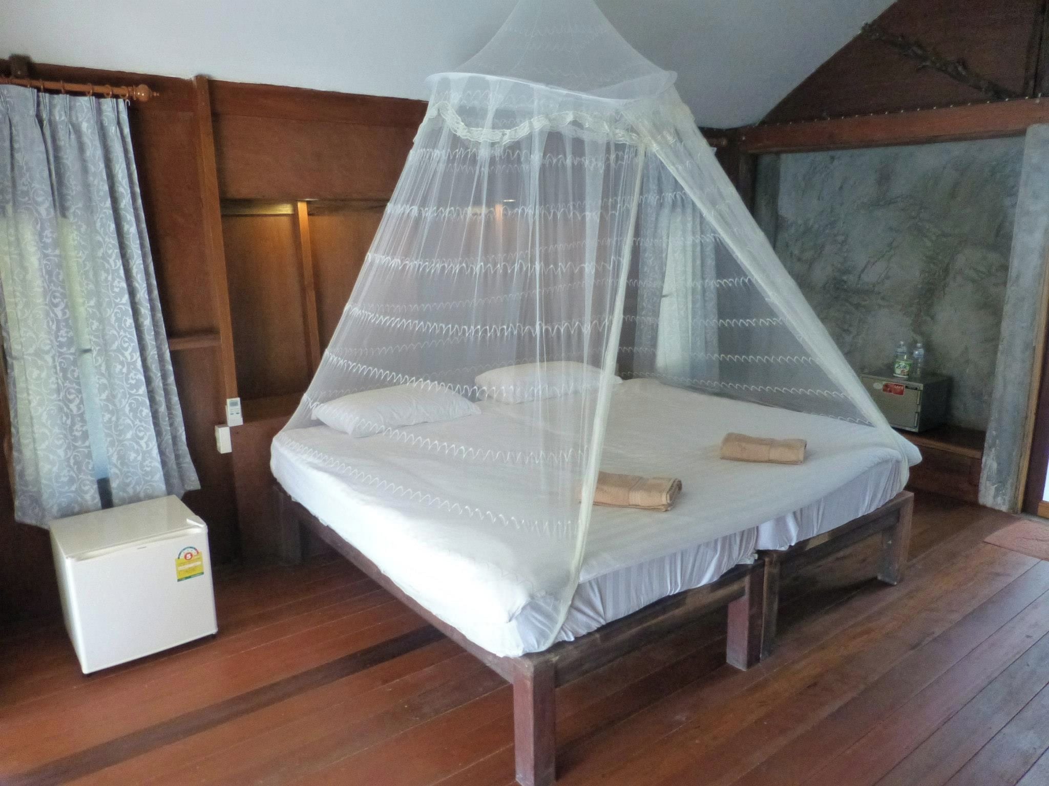 A single bed with a canopy in a room with wooden walls and a marble-like wall.