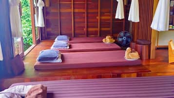 A room with two beds, a fan, and a small table with towels.