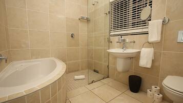 Un baño con bañera, lavamanos, inodoro y zona de ducha.