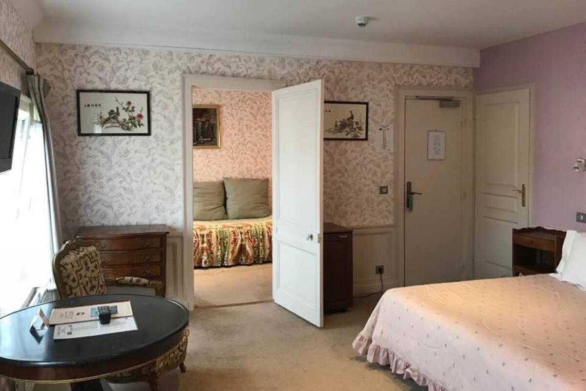 Une chambre d’hôtel comprenant un lit, un bureau, une chaise et une porte donnant sur une autre pièce.
