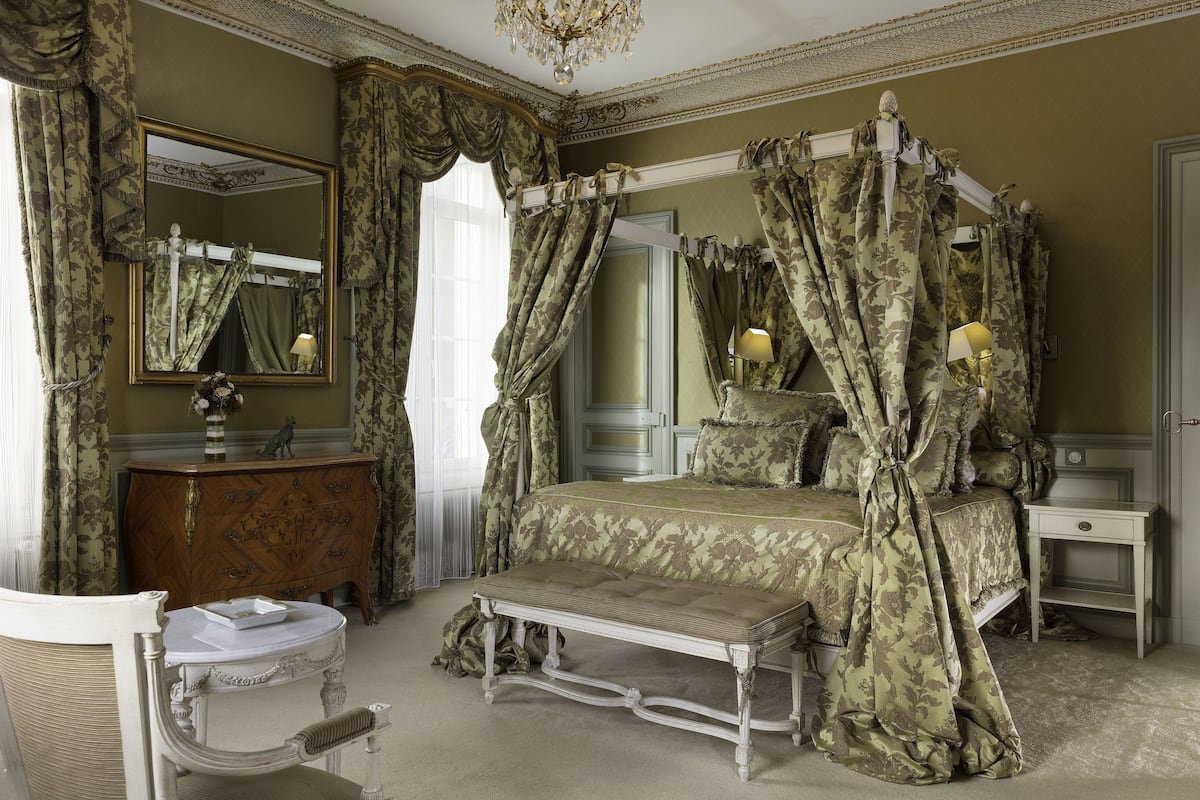 Une chambre à coucher avec un lit à baldaquin, une coiffeuse, une chaise et une petite table de chevet.