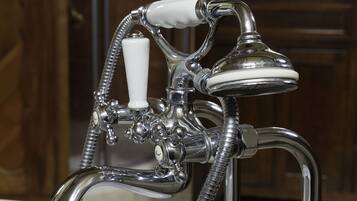A bathroom with a white bathtub, chrome fixtures, and a glass shower enclosure.