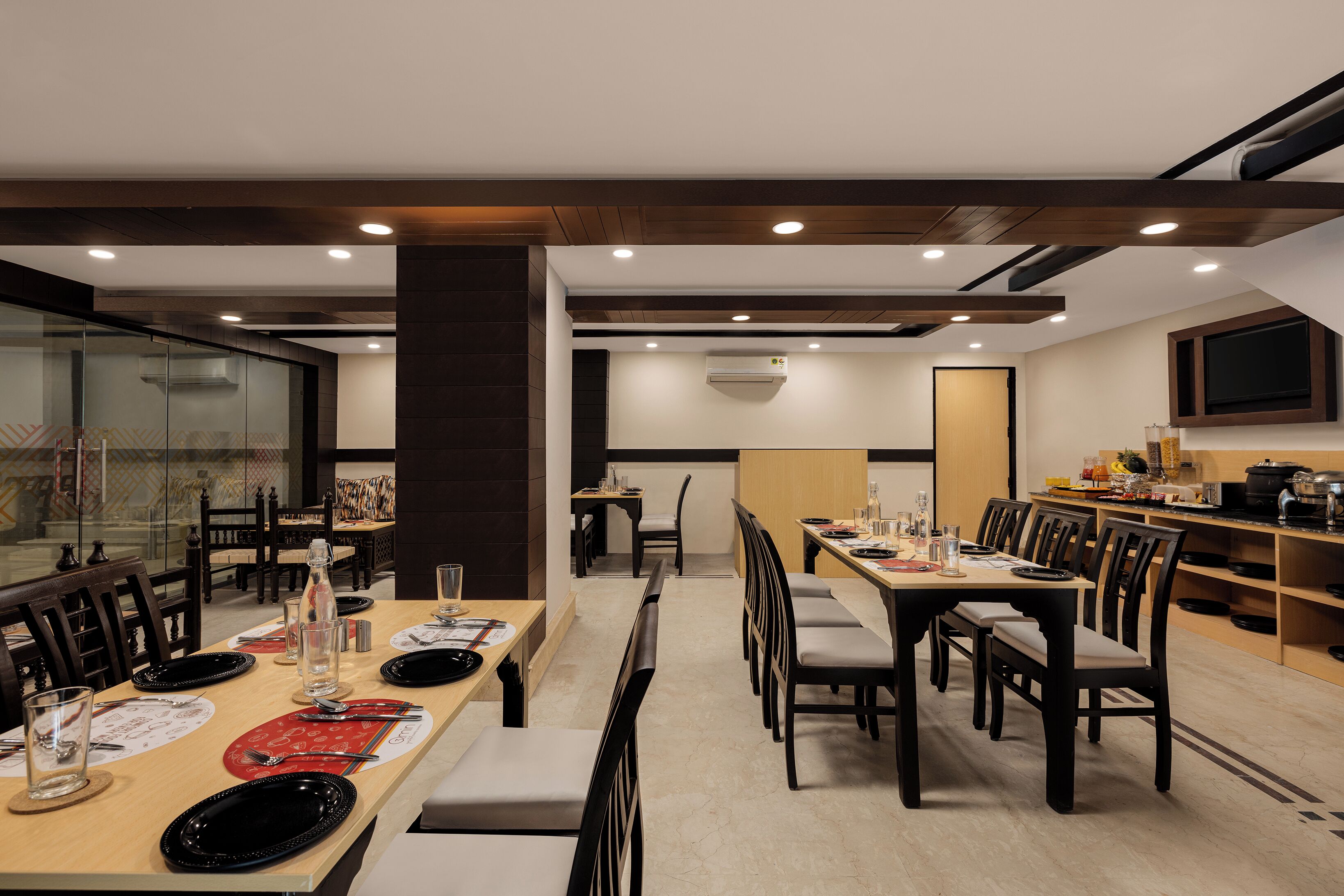 A restaurant with multiple dining tables, chairs, and a kitchen area.
