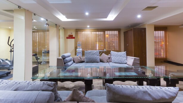 Un salón moderno con una mesa de centro de vidrio, sofás y vistas a una zona de ejercicios.