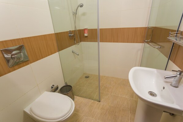 A bathroom with a glass-enclosed shower, a white sink, and a toilet.