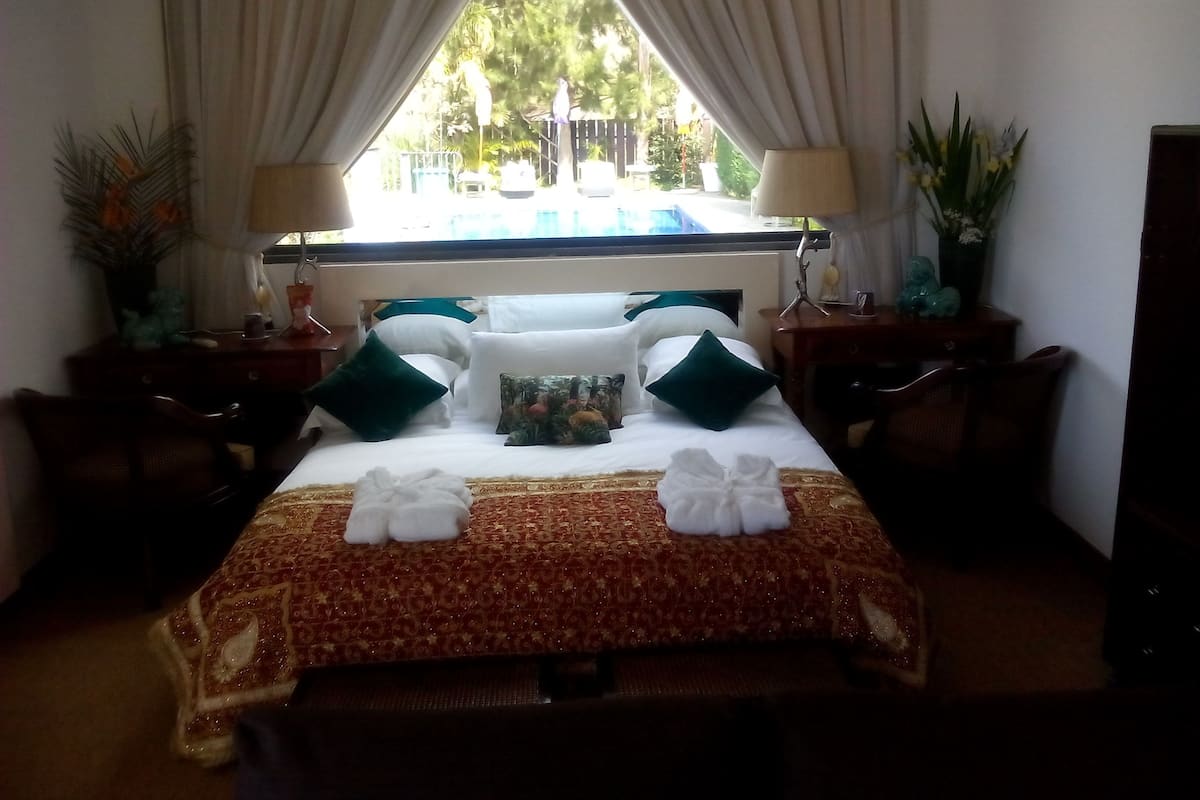 Habitación de hotel con cama, dos mesitas de noche, una ventana con cortinas y vistas al exterior.