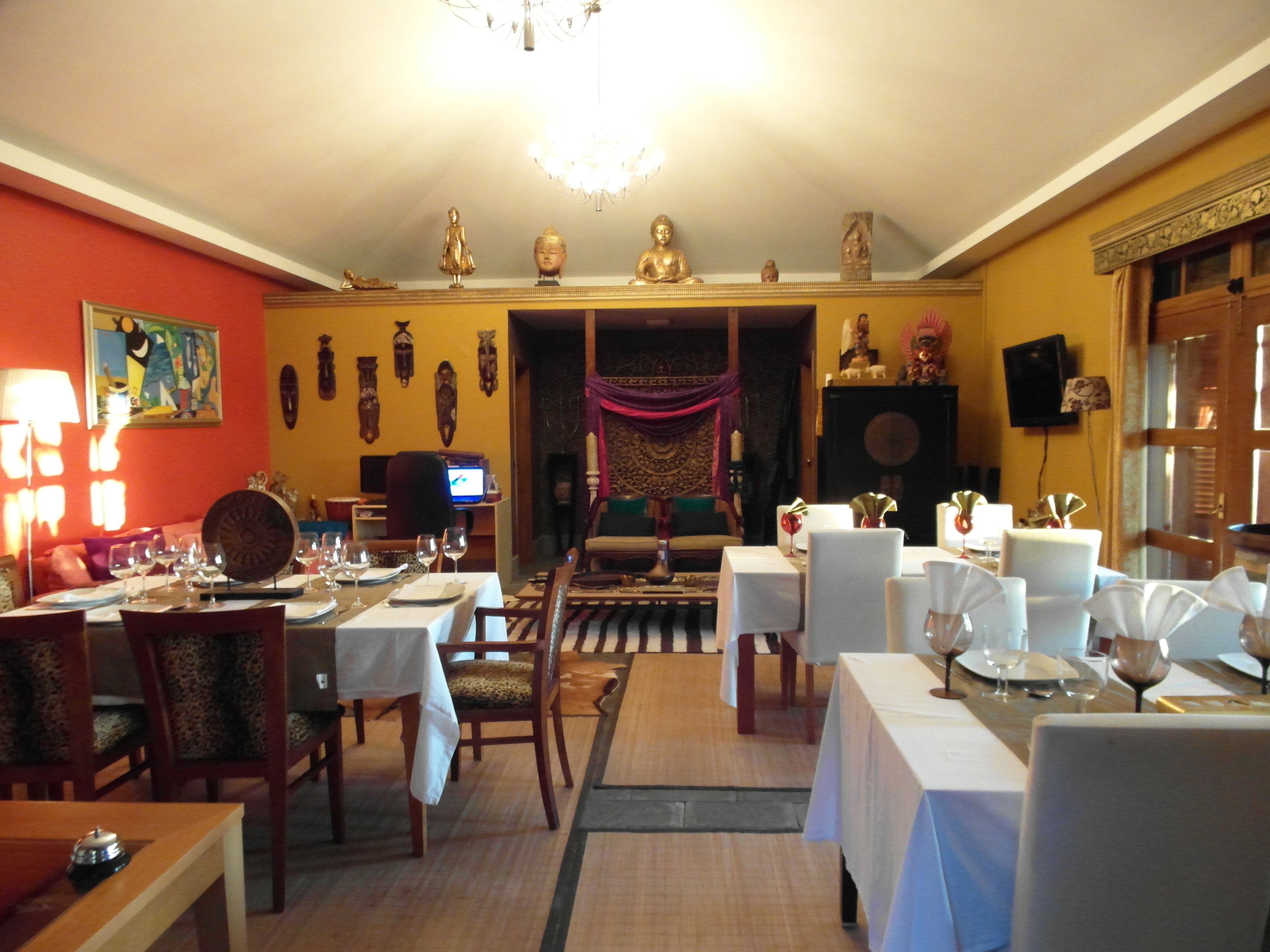 A dining area with tables set for a meal, chairs, and a television in the background.