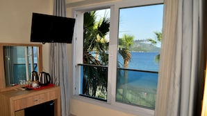 Habitación de hotel con un amplio ventanal que ofrece vistas al mar y palmeras.