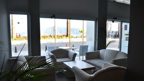 Un moderno vestíbulo de hotel con zona de estar, ventanas amplias y vistas al exterior.