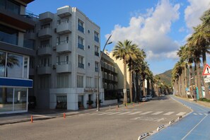A multi-story hotel with balconies, a pedestrian crossing, palm trees, and a clear sky.