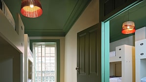 Une chambre avec des lits superposés, un plancher en bois, une porte verte et une fenêtre donnant sur un beau paysage.