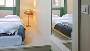 A small, narrow room with a bed, a bedside lamp, and a window. - 29 Madeira Hostel (Funchal)