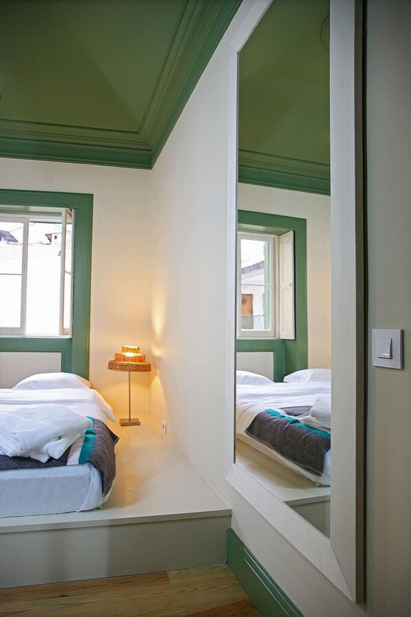 A small, narrow room with a bed, a bedside lamp, and a window. - 29 Madeira Hostel (Funchal)