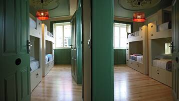 A room with bunk beds, a wooden floor, and a green door.
