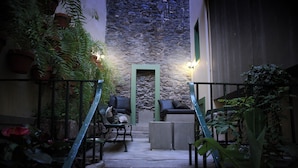 A staircase leading to a living area with a stone wall, green-framed door, and potted plants. - 29 Madeira Hostel (Funchal)