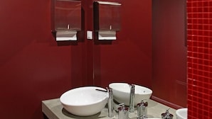 Une salle de bain avec deux lavabos, un miroir et un mur recouvert de carreaux rouges.