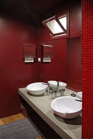 A bathroom with two sinks, a mirror, and a red-tiled wall. - 29 Madeira Hostel (Funchal)