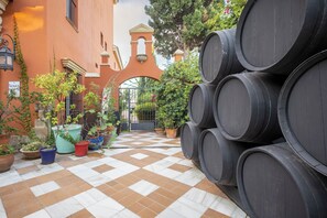 A courtyard with a tiled floor, potted plants, and stacked barrels. - Apartamentos Soho Boutique Vistahermosa  (El Puerto de Santa Maria)