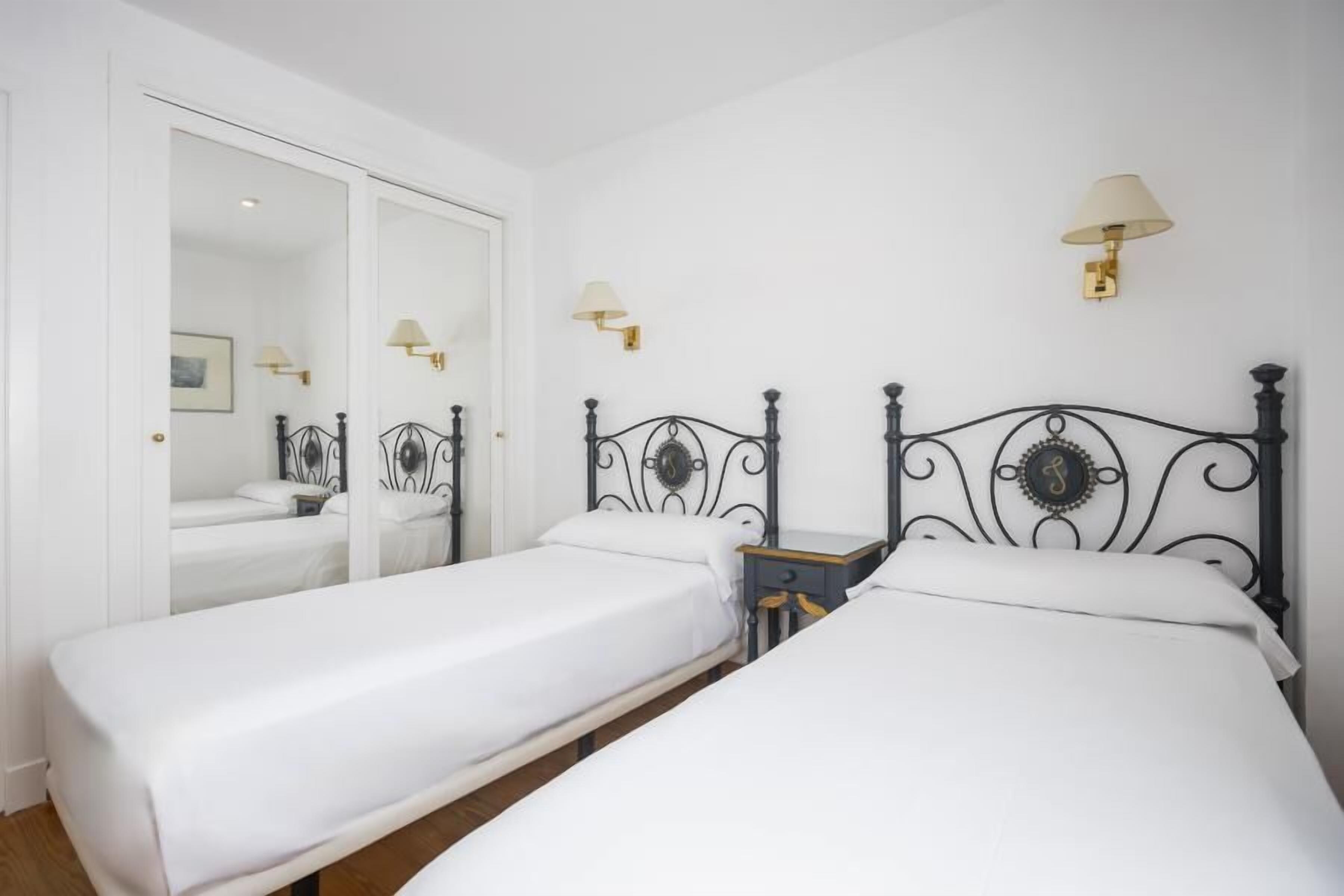 Una habitación con dos camas individuales, un armario y un espejo.