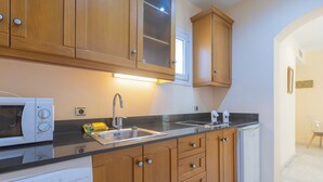 A modern kitchen with wooden cabinets, a double sink, a microwave, a dishwasher, and a refrigerator. - Apartamentos Soho Boutique Vistahermosa  (El Puerto de Santa Maria)