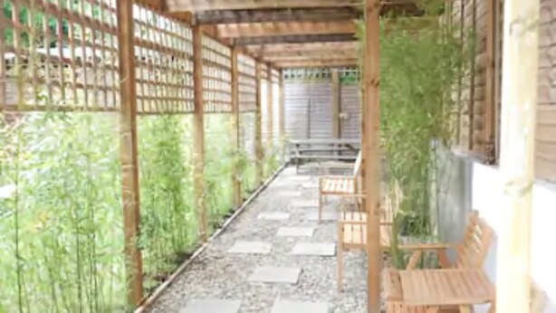 A covered outdoor seating area with wooden benches and a pergola structure. - 247 London Studios (London)