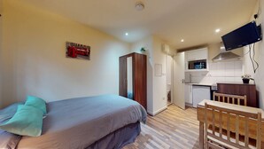 A compact room with a bed, a small kitchenette, and a TV mounted on the wall. - 247 London Studios (London)