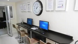 A reception area with a black reception desk, two computer monitors, a wall clock, and three bar stools. - 247 London Studios (London)