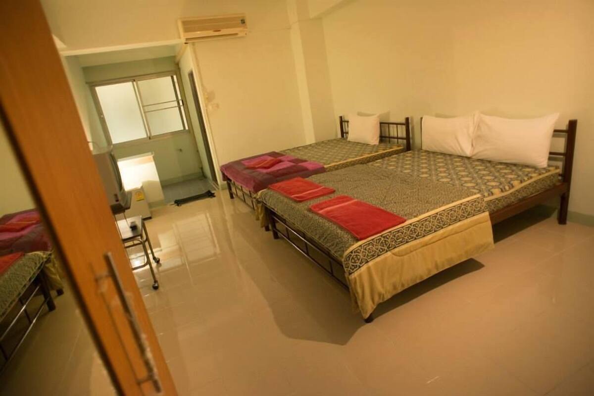 A room with two single beds, a wooden door, and a small table with a chair.