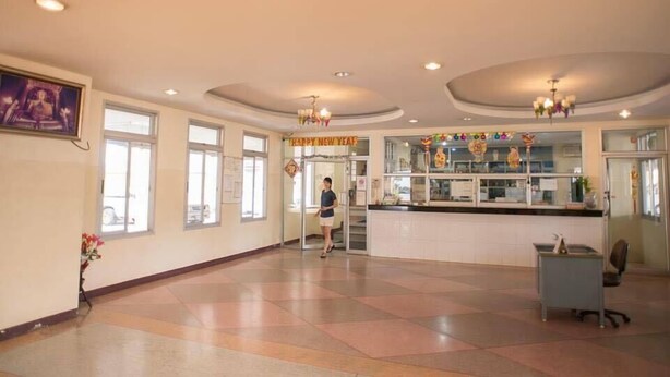 Un hall d’entrée spacieux avec un comptoir d’accueil, un escalier et une grande fenêtre.