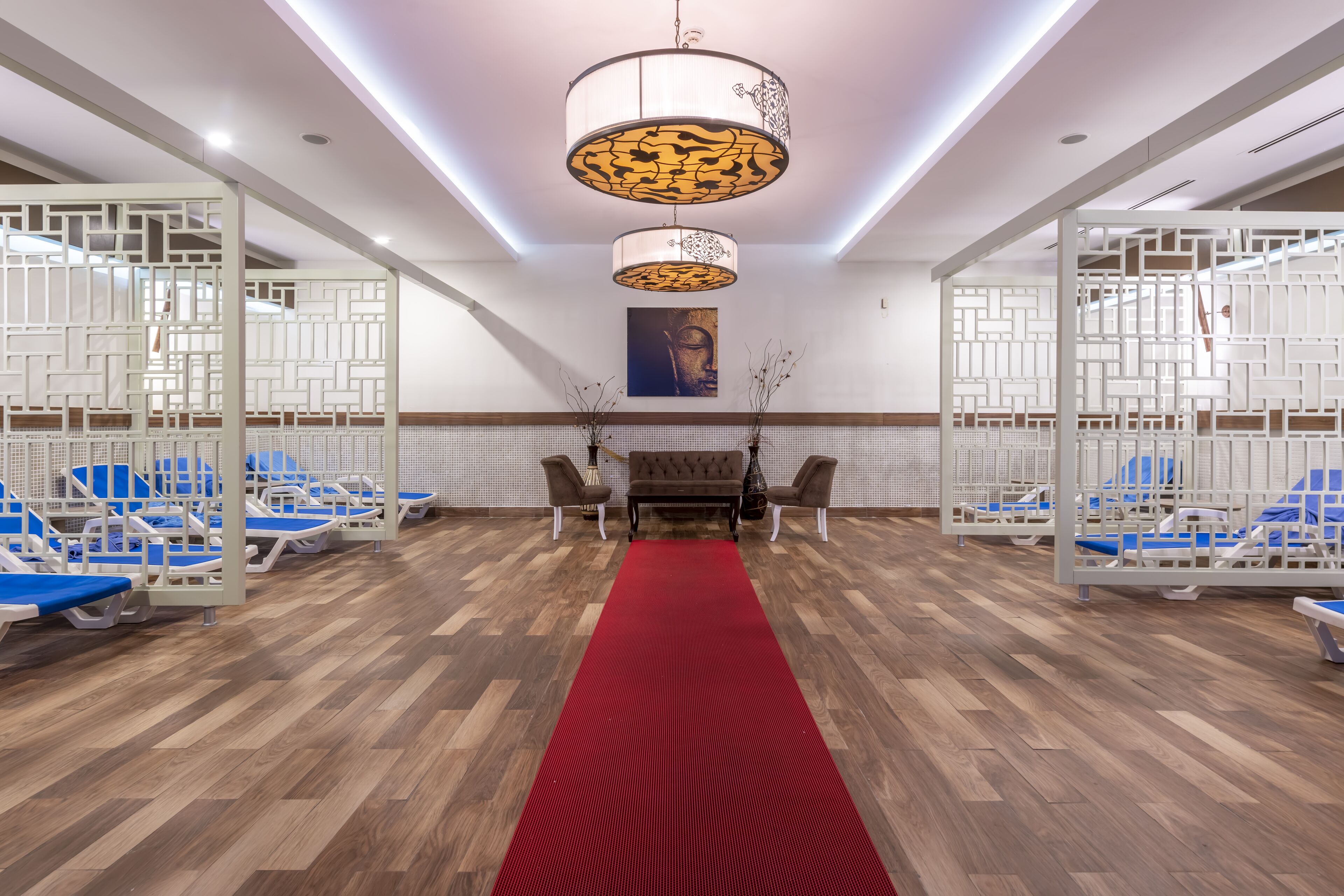 A hotel lobby with a red carpet, wooden flooring, and a large chandelier.