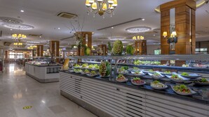 A buffet area with various food stations, a central decorative column, and overhead chandeliers. - Lake River Side Hotel Spa - Ultra All Inclusive (Manavgat)